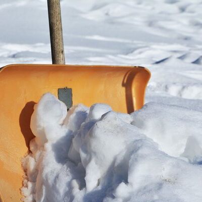 Das Foto zeigt eine holzfarbene Schneeschaufel mit Schnee 